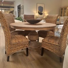 a dining room table with wicker chairs and a bowl on the centerpiece in front of it