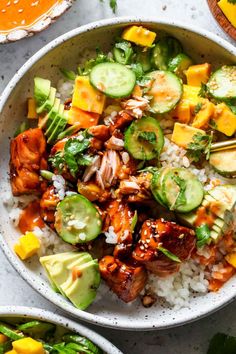 two bowls filled with chicken and vegetables on top of rice next to sliced cucumbers