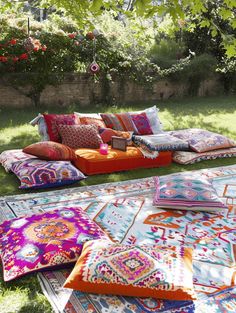 an outdoor seating area with colorful pillows and rugs