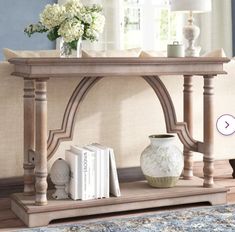 a white vase sitting on top of a wooden table next to a book shelf with books