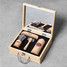 an open wooden box containing three grooming tools