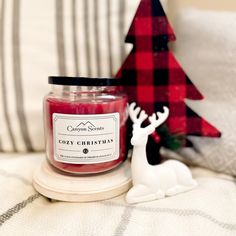 a small candle sitting on top of a bed next to a christmas tree and reindeer figurine