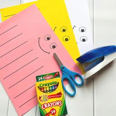 scissors, crayons, and construction paper are on the table next to each other