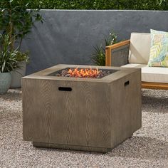 an outdoor fire pit sitting on top of a gravel ground next to a wooden bench