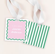 a pink and green striped gift tag with white ribbon on the side next to it