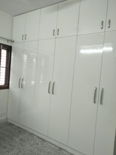 an empty room with white cupboards and carpeted flooring in front of a window