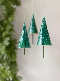 three green plastic christmas trees hanging from strings