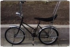 a black bike parked on the side of a street next to a sidewalk with grass