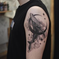 a man with a tattoo on his arm has a whale in the sky and stars around it