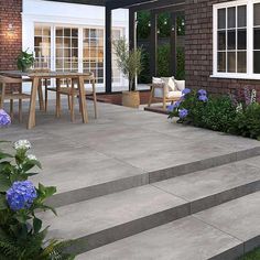 an outdoor patio with steps leading up to the dining room and sitting area, surrounded by blue hydrangeas