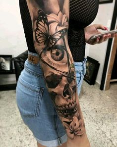 a woman's arm with a skull and butterfly tattoo on the left side of her body