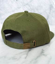 Rep Sugar Land in style with this classic cotton twill hat, in crisp Olive color. Featuring 6-panel construction, this hat is decorated with our vintage emblem design embossed on round leather patch and finished with contrast stitch. With a flat bill and breathable material, it's just the right hat to have for hot summer days. Fitted with a brass buckle on the back strap for easy size adjustment. Also available in Atlantic Blue color. Military Style Snapback Baseball Cap In Cotton, Classic Snapback Hat With Embroidered Logo And Curved Brim, Casual Fitted Flat Cap With Logo Patch, Military Style Cotton Baseball Cap For Streetwear, Classic Green Baseball Cap For Outdoor, Outdoor Fitted Cap With Logo Patch, Classic Trucker Hat With Logo Patch And Curved Brim, Classic Flat Bill Hat With Embroidered Logo, Outdoor Fitted Hat With Flat Brim And Embroidered Logo