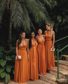 four women in orange dresses standing on steps