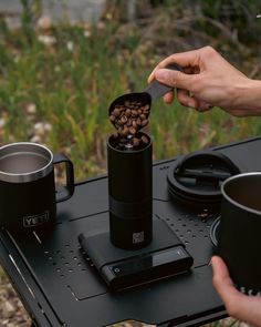 a person pouring coffee into a cup on top of a table with two mugs