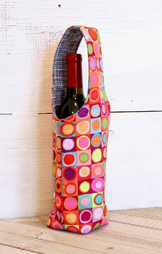 a wine bag with a bottle in it sitting on a wooden table next to a white wall