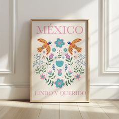 a framed poster with the words mexico on it in front of a white wall and wooden floor