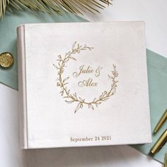 a wedding guest book and pen sitting on top of a table next to pine branches