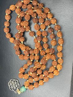 a necklace with beads and a cross on the clasp is laying on a black surface