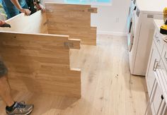 two men are working on an unfinished kitchen counter top with wood planks in the foreground