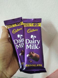 two cadbury dairy milk chocolate bars in their hand