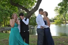 a man and woman kissing while standing next to each other in front of a lake