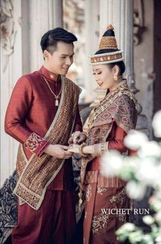 a man and woman dressed in traditional thai garb standing next to each other holding hands