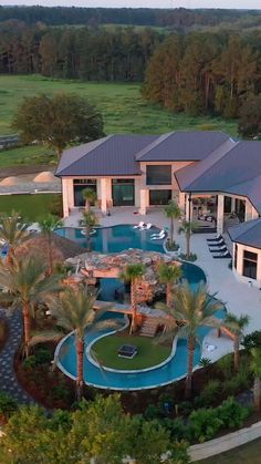 an aerial view of a house with a pool in the foreground and palm trees surrounding it