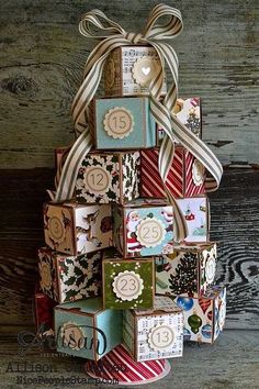 a small christmas tree made out of many different types of cards and ribbons on a wooden table