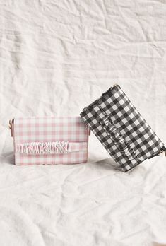 The classic clutch has been updated in a fun gingham print. Available in both black/ white and pink/white, this style features a hand strap for easy carrying and as well as an optional shoulder strap. Pair with a classic white dress and sandals for an everyday spring look. White Bags For Spring Picnic, Rectangular Gingham Bags For Summer, Gingham Bags For Daily Use In Spring, Spring Gingham Bags For Daily Use, Spring Gingham Bag For Daily Use, Spring Plaid Rectangular Bags, Chic White Bag For Picnic, Gingham Bags For Spring Travel, Dress And Sandals