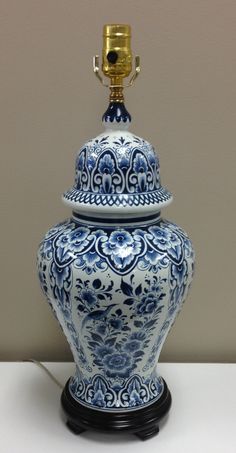 an ornate blue and white urn with a gold top on a table in front of a wall