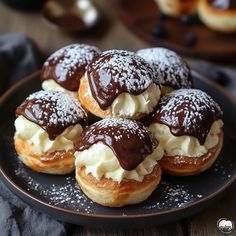 chocolate covered donuts on a black plate with powdered sugar and sprinkles