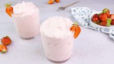 two glasses filled with ice cream and strawberries on top of a white tablecloth