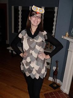 a woman standing in front of a fireplace wearing an owl hat and scarf over her head