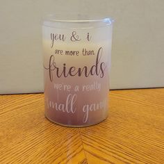 a candle that is on top of a wooden table with words written on the jar