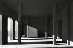 black and white photograph of an empty room with columns in the center, sunlight coming through the windows