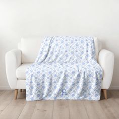 a white chair with a blue blanket on it in front of a white wall and wooden floor