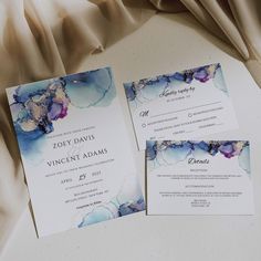 wedding stationery with blue and purple watercolors on it's front and back