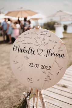 a wooden sign with writing on it sitting on top of a wooden table next to an umbrella