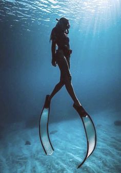 a scuba diver is silhouetted against the blue water