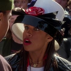 a woman wearing a black and white hat with a rose on it's brim