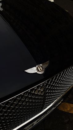 the front end of a black car with a bentley emblem on it's grill