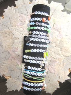 a stack of bracelets sitting on top of a wooden table next to a leaf