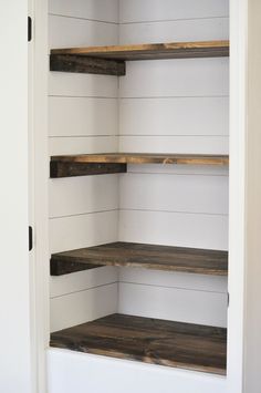 an empty shelf in the corner of a room with white walls and wood shelves on each side