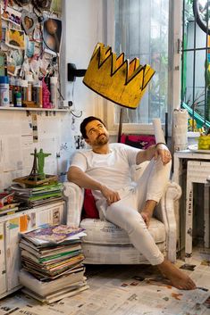 a man sitting in a chair with a crown on top of his head and newspaper all over the floor