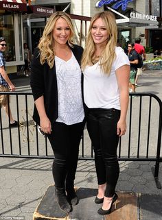 two beautiful women standing next to each other in front of a sign that says dodgers