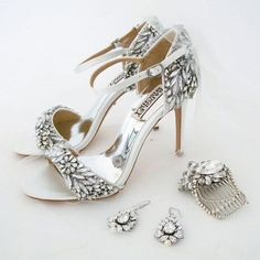 a pair of white high heeled shoes next to a hair comb and ear clips