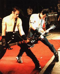 two young men playing guitars on stage