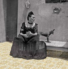 an old photo of a woman sitting on the ground with a dog in front of her