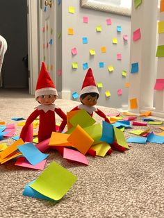 two elfs sitting on the floor surrounded by post - it notes and paper streamers