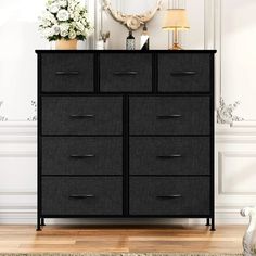 a black dresser sitting on top of a hard wood floor next to a white wall